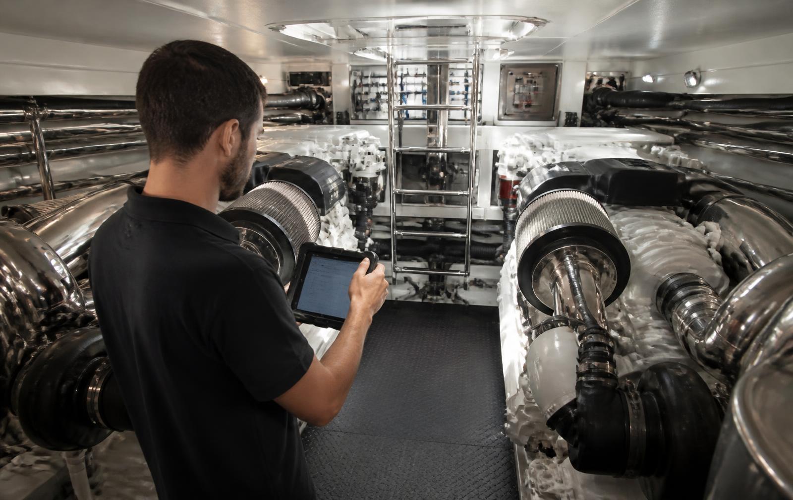 Engineer inspecting the engine room of a large yacht with a tablet